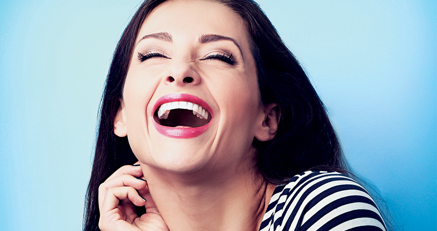 Woman with white teeth tilts head back and smiles